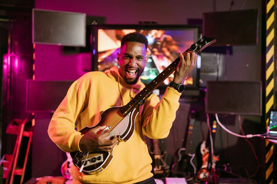 A guitarist using a metal slide on their ring finger, sliding up the neck of an electric guitar